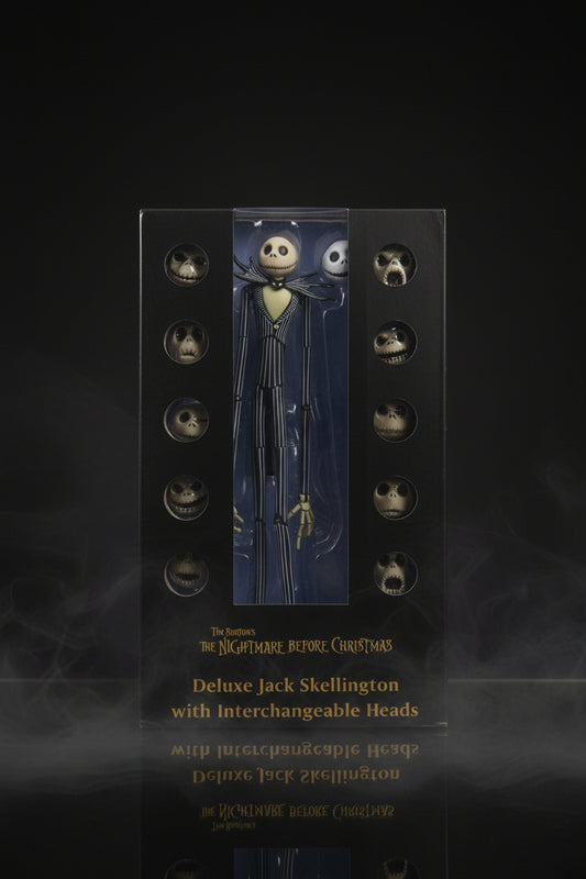 A boxed collectible figure of The Nightmare Before Christmas Deluxe Jack Skellington with interchangeable heads, shown in its retail packaging with a hand holding it.